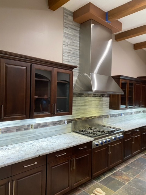 Eat-in kitchen - mid-sized l-shaped exposed beam eat-in kitchen idea in Phoenix with an undermount sink, raised-panel cabinets, dark wood cabinets, granite countertops, gray backsplash, glass tile bac