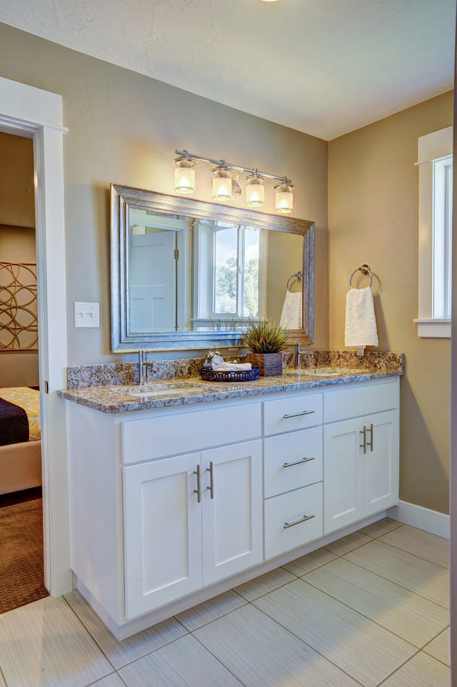 Design ideas for a mid-sized traditional master bathroom in Salt Lake City with shaker cabinets, white cabinets, an alcove tub, a shower/bathtub combo, a one-piece toilet, beige tile, glass tile, beige walls, porcelain floors, an undermount sink and granite benchtops.