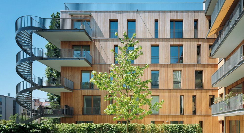 Photo of a large contemporary three-storey brown apartment exterior in Other with wood siding and a flat roof.