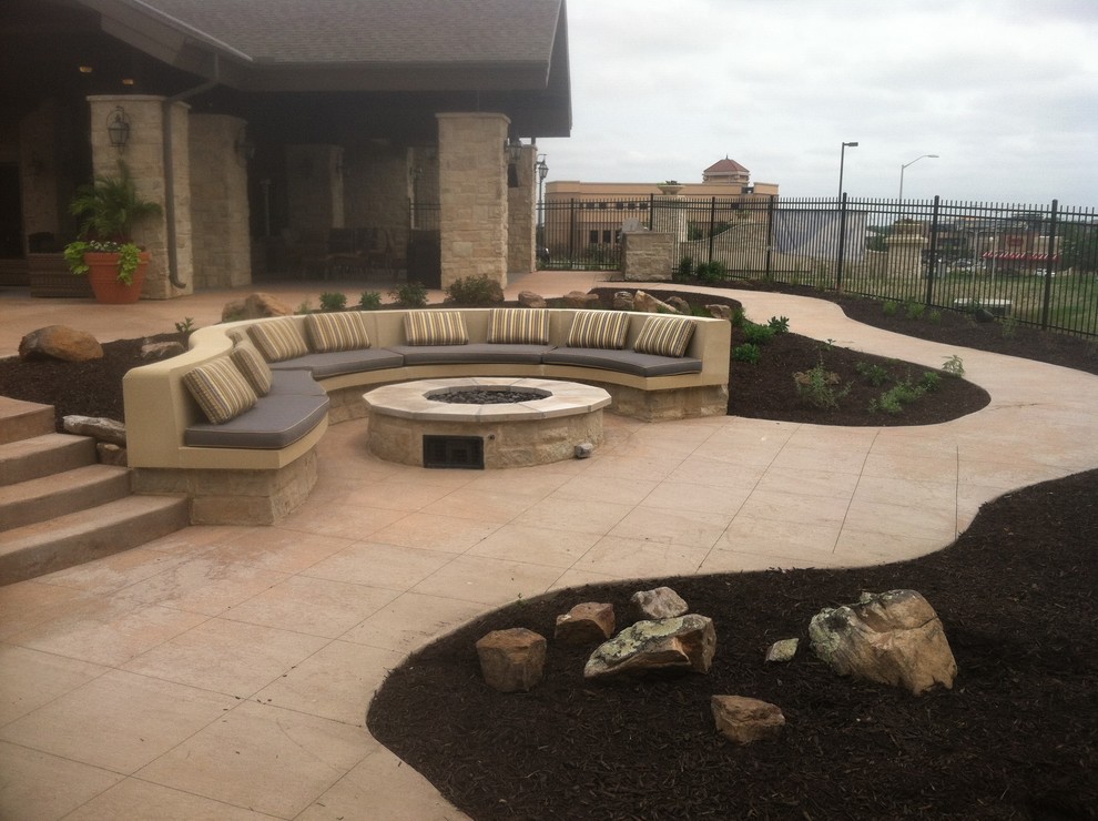 Photo of a large mediterranean backyard patio in Kansas City with a fire feature, concrete pavers and a roof extension.