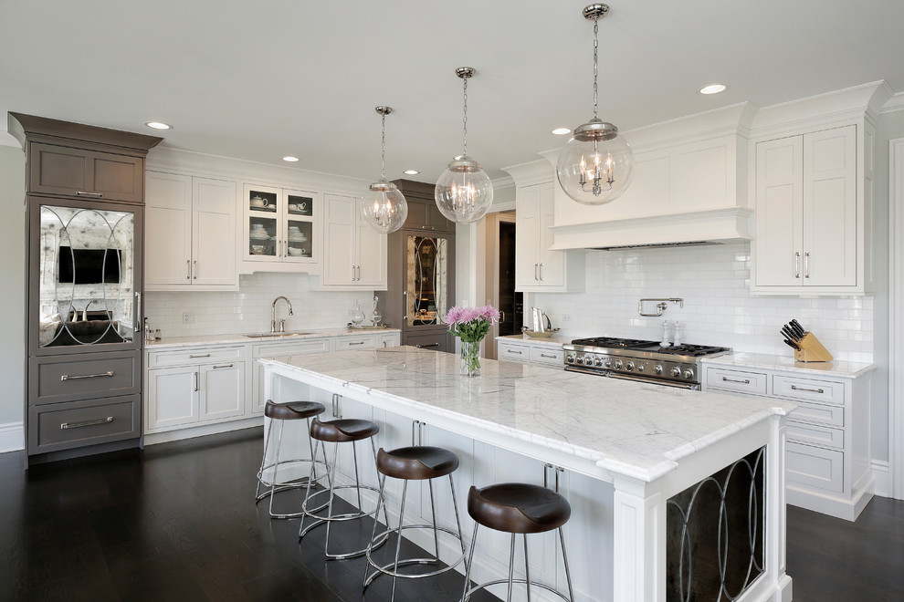 Photo of a large traditional kitchen in Chicago with white cabinets, white splashback, dark hardwood floors, with island, an undermount sink, shaker cabinets, subway tile splashback and stainless steel appliances.