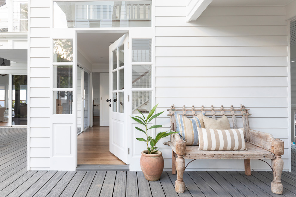 Mid-sized tropical front door in Sunshine Coast with white walls, light hardwood floors, a single front door, a white front door and grey floor.