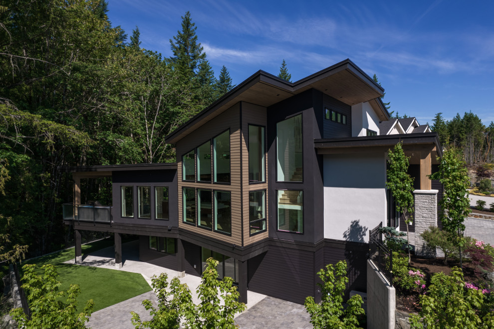 Mittelgroßes, Dreistöckiges Modernes Einfamilienhaus mit Faserzement-Fassade, beiger Fassadenfarbe, Schmetterlingsdach, Blechdach, schwarzem Dach und Verschalung in Vancouver