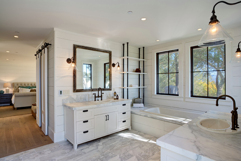 Design ideas for a mid-sized country master bathroom in San Francisco with marble benchtops, flat-panel cabinets, medium wood cabinets, an open shower, a one-piece toilet, beige tile, stone slab, beige walls, ceramic floors, a drop-in sink, a drop-in tub and grey floor.