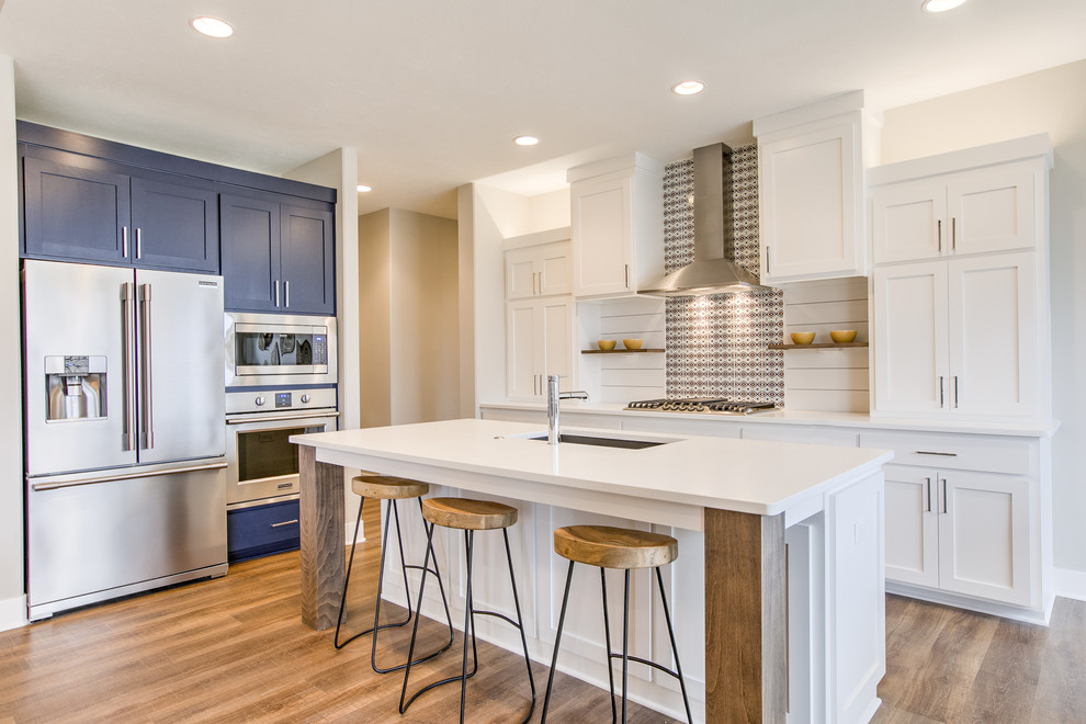 Inspiration for a transitional l-shaped brown floor open concept kitchen remodel in Omaha with an undermount sink, shaker cabinets, quartz countertops, stainless steel appliances, an island, white countertops, blue cabinets and multicolored backsplash