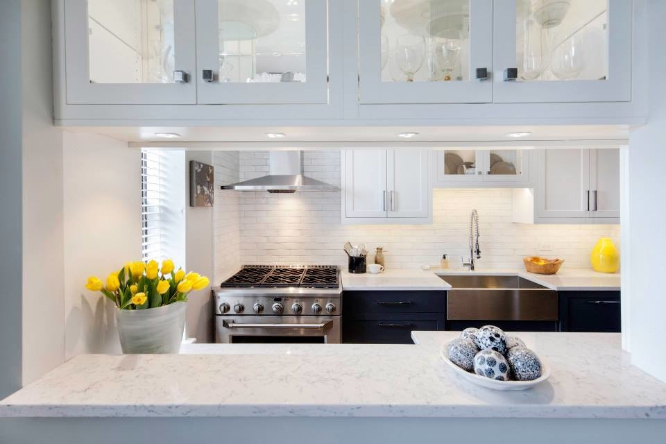 Transitional separate kitchen in New York with a farmhouse sink, shaker cabinets, white cabinets, quartz benchtops, white splashback, stainless steel appliances and light hardwood floors.