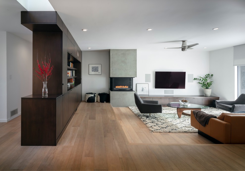 Design ideas for a large contemporary open concept living room in San Francisco with white walls, light hardwood floors, a plaster fireplace surround, a wall-mounted tv, a two-sided fireplace and brown floor.