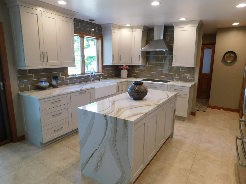 Inspiration for a transitional l-shaped porcelain tile and beige floor eat-in kitchen remodel with a farmhouse sink, flat-panel cabinets, quartz countertops, gray backsplash, porcelain backsplash, stainless steel appliances and an island