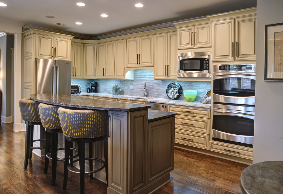 Example of a mid-sized transitional galley medium tone wood floor open concept kitchen design with an undermount sink, stainless steel appliances, gray walls, an island, raised-panel cabinets, beige cabinets and granite countertops