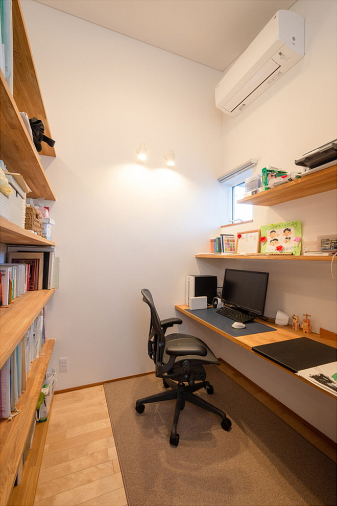 Mittelgroßes Arbeitszimmer mit Arbeitsplatz, weißer Wandfarbe, hellem Holzboden, Tapetendecke und Tapetenwänden in Sonstige