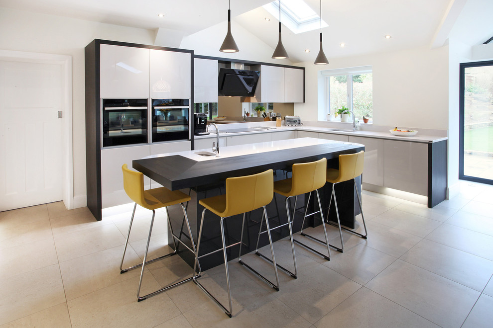 Design ideas for a contemporary kitchen in Manchester with an undermount sink, flat-panel cabinets, white cabinets, glass sheet splashback, black appliances and with island.