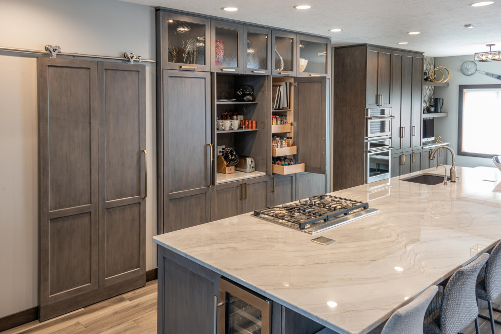 Kitchen - large transitional medium tone wood floor and brown floor kitchen idea with a single-bowl sink, flat-panel cabinets, gray cabinets, quartzite countertops, gray backsplash, marble backsplash, paneled appliances, an island and white countertops