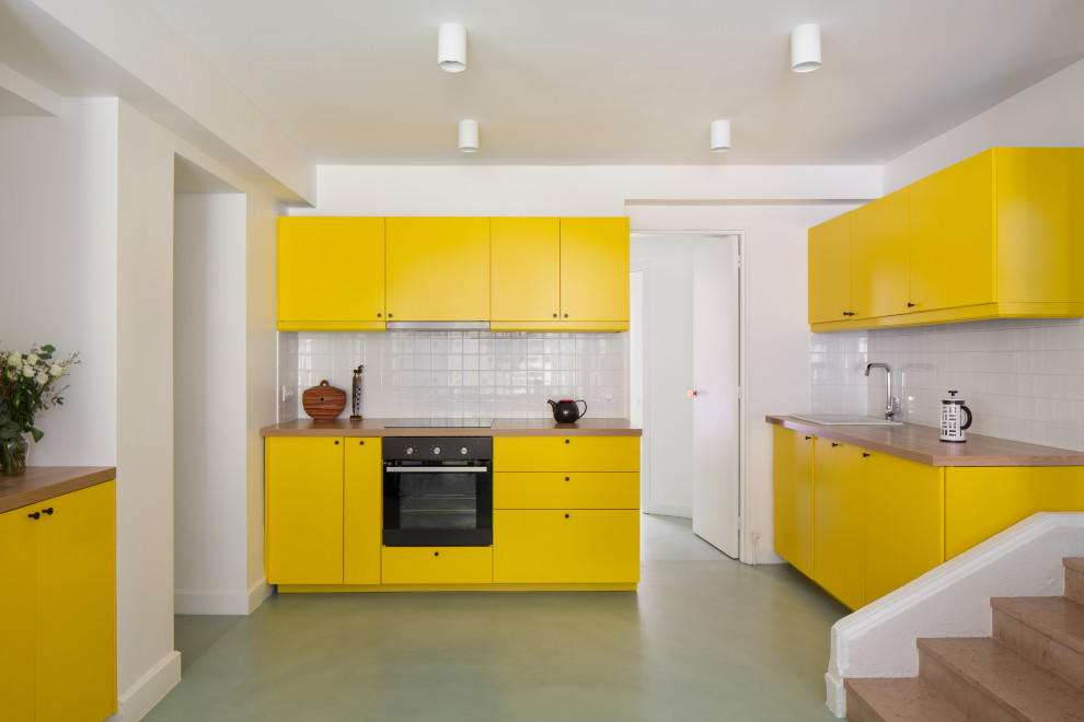 Inspiration for a mid-sized contemporary u-shaped kitchen in Paris with a drop-in sink, flat-panel cabinets, yellow cabinets, wood benchtops, white splashback, ceramic splashback, no island, green floor and beige benchtop.