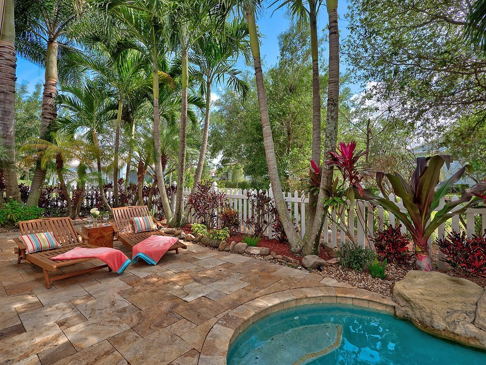 This is an example of a mid-sized tropical backyard patio in New York with concrete pavers and no cover.