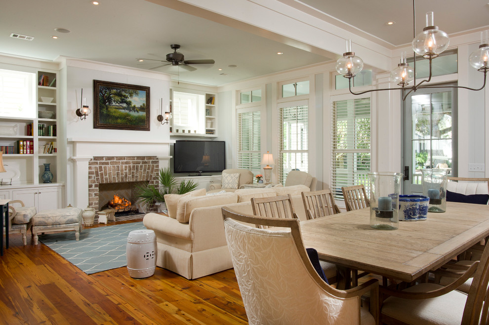 Photo of a beach style open concept living room in Atlanta with medium hardwood floors, a brick fireplace surround and a freestanding tv.