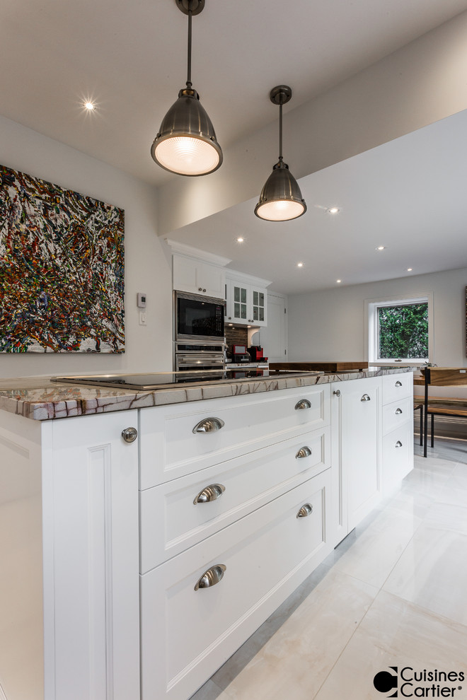 This is an example of a large transitional l-shaped eat-in kitchen in Montreal with an undermount sink, shaker cabinets, white cabinets, granite benchtops, brown splashback, porcelain splashback, panelled appliances, ceramic floors and with island.