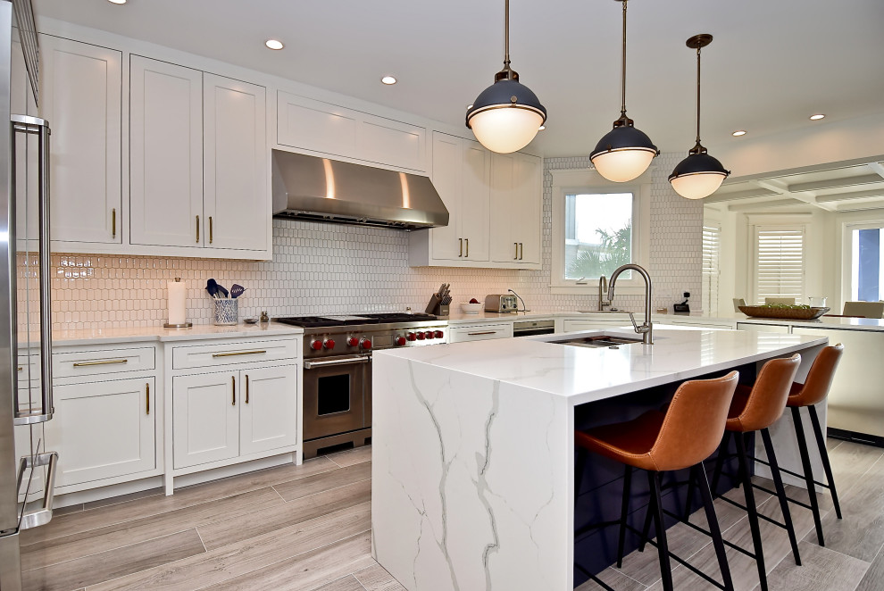 Design ideas for a large beach style u-shaped eat-in kitchen in Tampa with a single-bowl sink, beaded inset cabinets, white cabinets, quartz benchtops, white splashback, ceramic splashback, stainless steel appliances, porcelain floors, with island, beige floor and white benchtop.