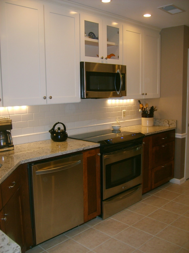 Eat-in kitchen - transitional galley eat-in kitchen idea with an undermount sink, shaker cabinets, dark wood cabinets, quartz countertops, white backsplash, subway tile backsplash and stainless steel appliances