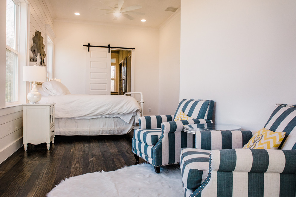 This is an example of a mid-sized beach style guest bedroom in Dallas with white walls, dark hardwood floors, no fireplace and brown floor.