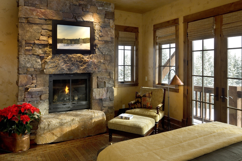 Country bedroom in Other with a stone fireplace surround.