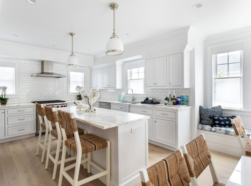 Example of a mid-sized minimalist u-shaped medium tone wood floor eat-in kitchen design in New York with an undermount sink, shaker cabinets, white cabinets, granite countertops, white backsplash, subway tile backsplash, stainless steel appliances, an island and white countertops