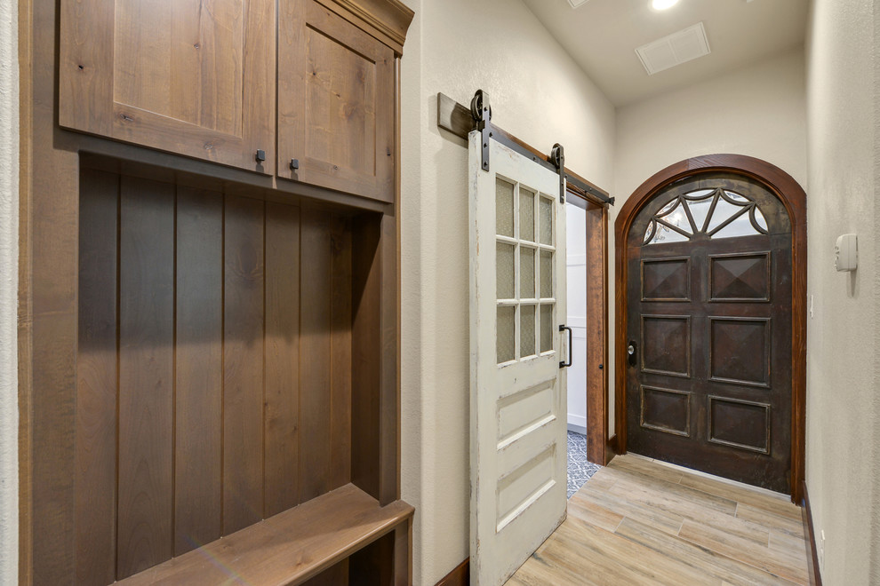Inspiration for a rustic ceramic tile and brown floor mudroom remodel in Austin with beige walls and a brown front door