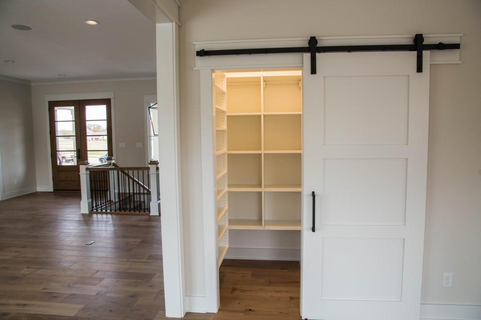 Inspiration for a large contemporary gender-neutral medium tone wood floor and brown floor walk-in closet remodel in Indianapolis with white cabinets