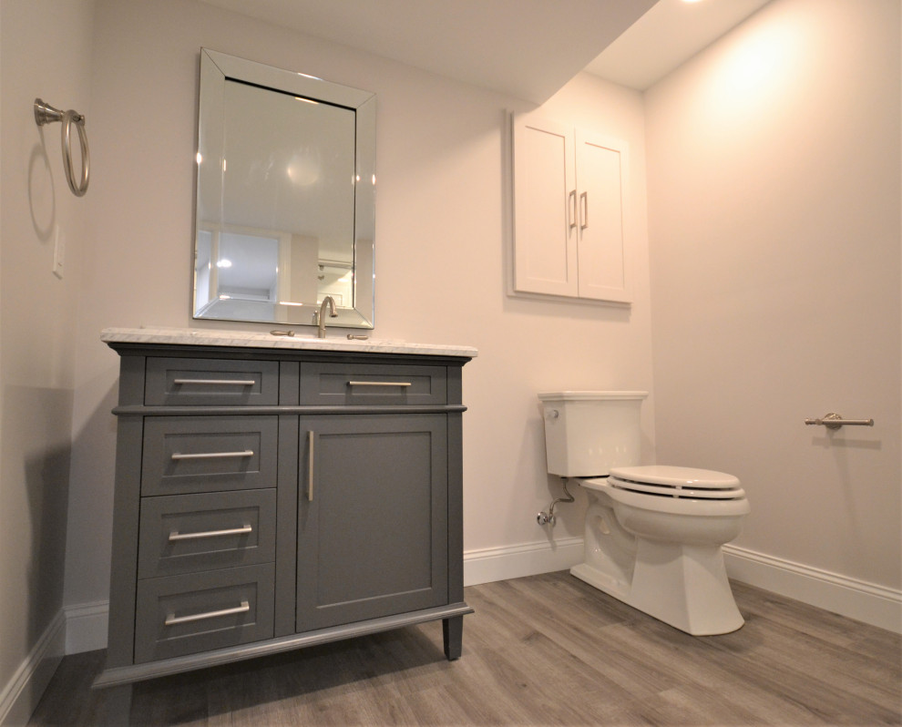 Large transitional 3/4 vinyl floor, beige floor and single-sink bathroom photo in Philadelphia with recessed-panel cabinets, gray cabinets, a one-piece toilet, beige walls, an undermount sink, quartzite countertops, white countertops and a freestanding vanity