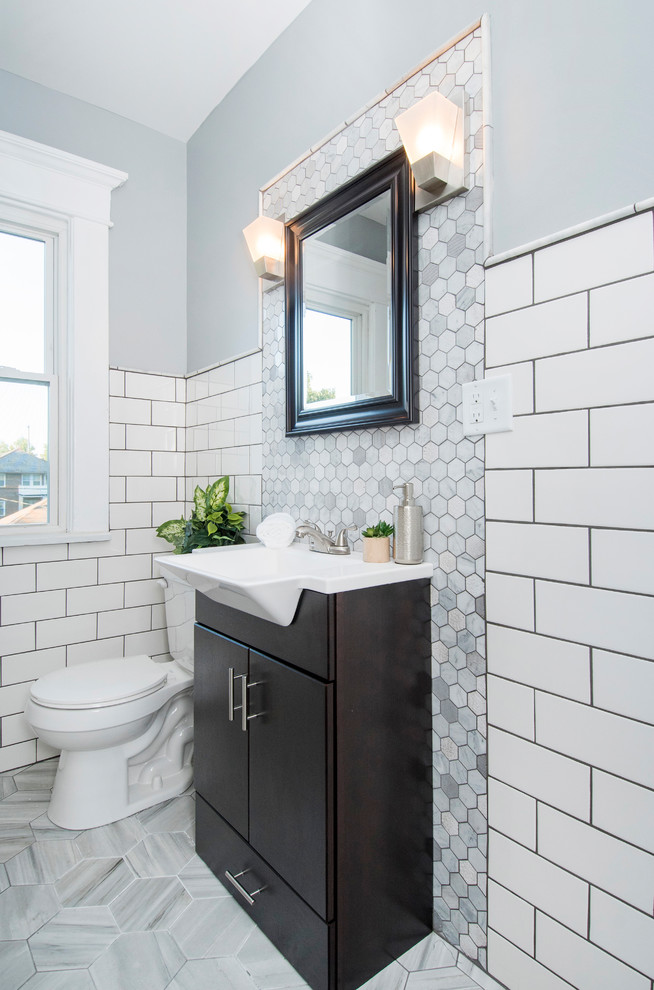 This is an example of a transitional bathroom in Columbus with flat-panel cabinets, dark wood cabinets, a two-piece toilet, white tile, subway tile, grey walls and a console sink.