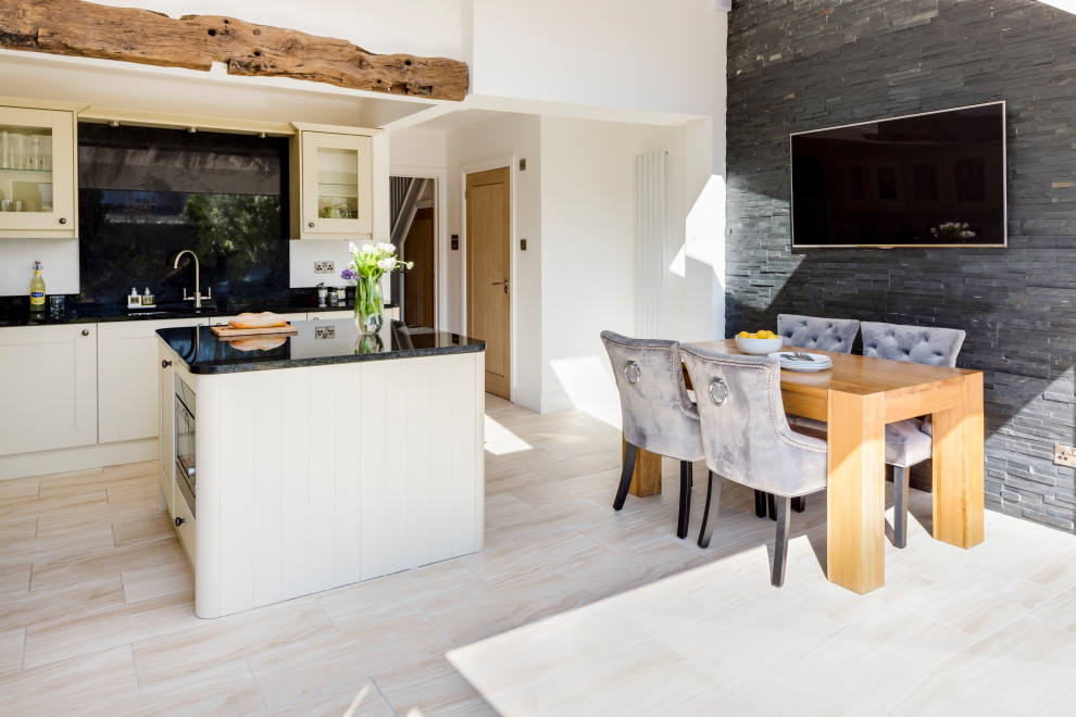 Photo of a large transitional l-shaped open plan kitchen in West Midlands with a double-bowl sink, glass-front cabinets, white cabinets, granite benchtops, black splashback, laminate floors, with island, black benchtop and exposed beam.