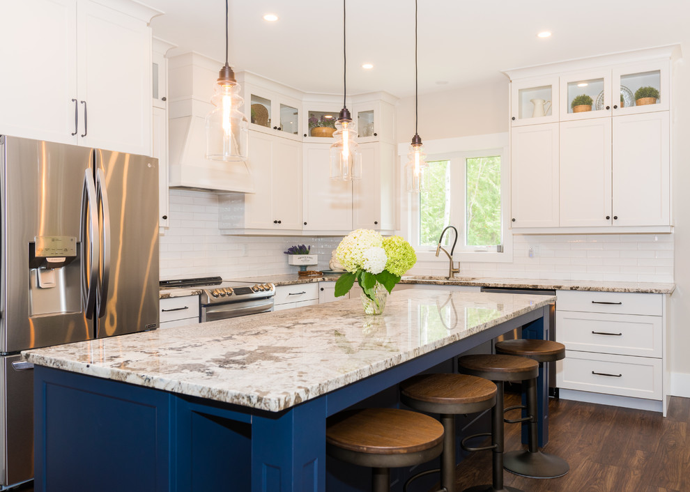 Design ideas for a transitional kitchen in Toronto with an undermount sink, shaker cabinets, blue cabinets, granite benchtops, white splashback, limestone splashback, stainless steel appliances, medium hardwood floors, with island, brown floor and multi-coloured benchtop.