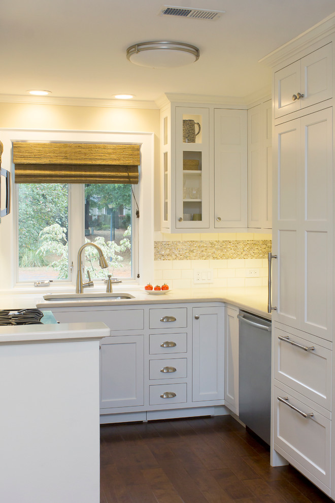 Inspiration for a small transitional u-shaped eat-in kitchen in Raleigh with an undermount sink, recessed-panel cabinets, white cabinets, quartz benchtops, white splashback, subway tile splashback, stainless steel appliances, dark hardwood floors, no island, brown floor and beige benchtop.