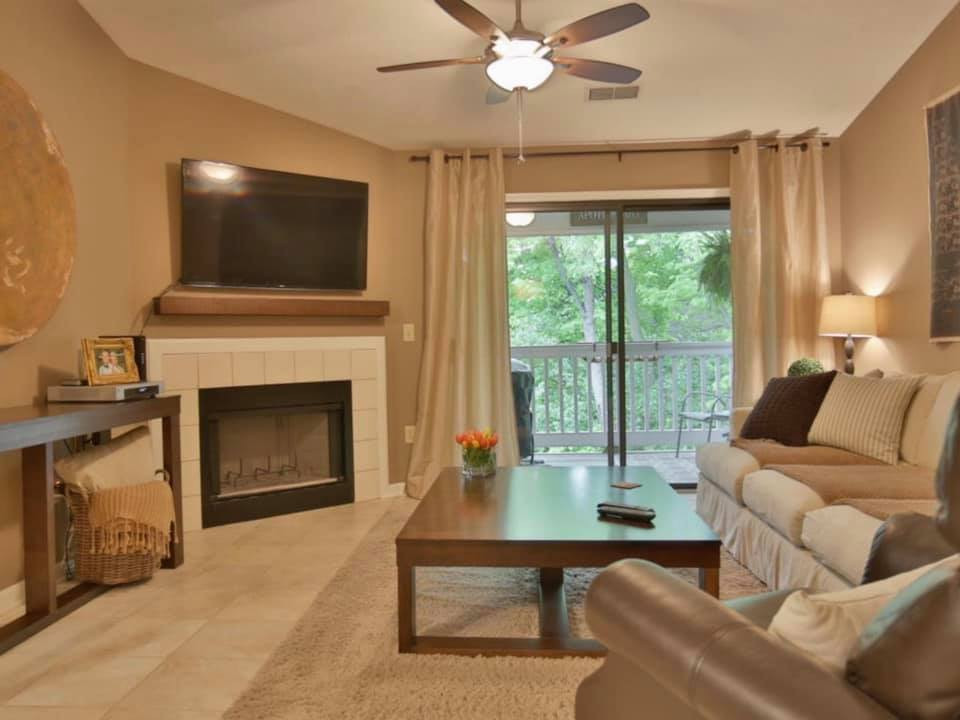 ルイビルにあるお手頃価格の広いトランジショナルスタイルのおしゃれなリビング (茶色い壁、セラミックタイルの床、標準型暖炉、壁掛け型テレビ、ベージュの床) の写真