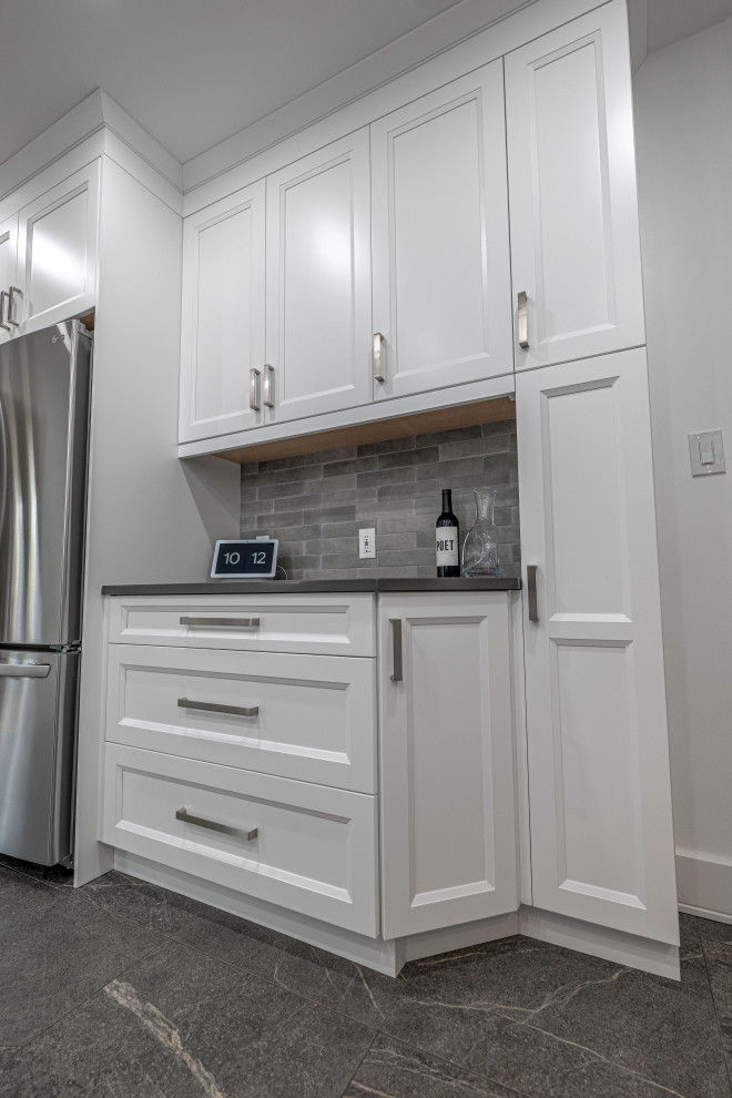 Example of a mid-sized transitional galley enclosed kitchen design with an undermount sink, shaker cabinets, white cabinets, quartz countertops, gray backsplash, subway tile backsplash, stainless steel appliances, no island and gray countertops