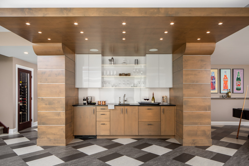 This is an example of a mid-sized contemporary galley home bar in Minneapolis with an undermount sink, flat-panel cabinets, medium wood cabinets, granite benchtops, white splashback, ceramic floors and black benchtop.