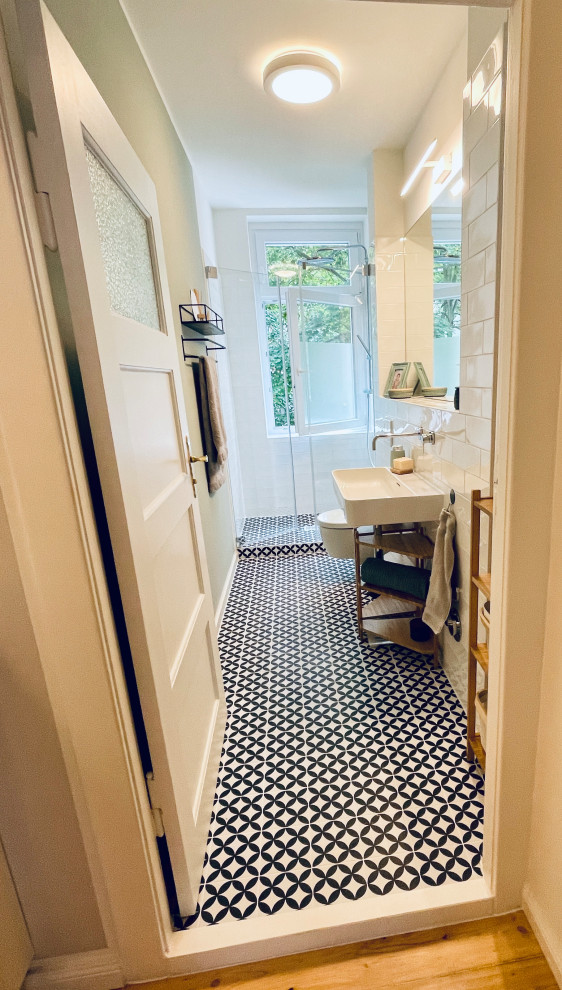 Inspiration for a mid-sized scandinavian 3/4 bathroom in Berlin with flat-panel cabinets, an alcove shower, a wall-mount toilet, white tile, ceramic tile, white walls, porcelain floors, a vessel sink, a hinged shower door, a single vanity and a freestanding vanity.