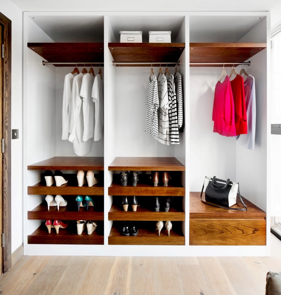 Design ideas for a mid-sized contemporary gender-neutral walk-in wardrobe in London with medium wood cabinets, light hardwood floors, beige floor and open cabinets.