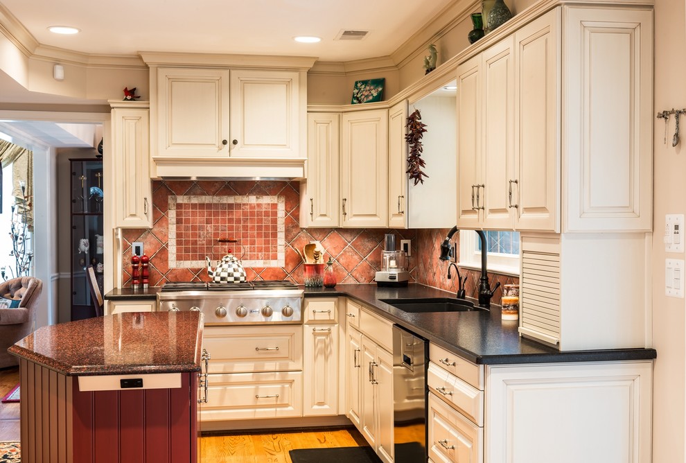 This is an example of a mid-sized mediterranean u-shaped eat-in kitchen in DC Metro with an undermount sink, raised-panel cabinets, white cabinets, granite benchtops, red splashback, ceramic splashback, stainless steel appliances, light hardwood floors and with island.