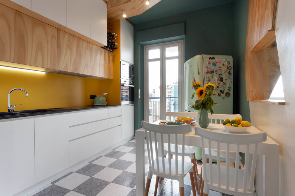 This is an example of a small scandinavian single-wall separate kitchen in Turin with a drop-in sink, flat-panel cabinets, light wood cabinets, laminate benchtops, yellow splashback, ceramic floors, no island, grey floor and black benchtop.