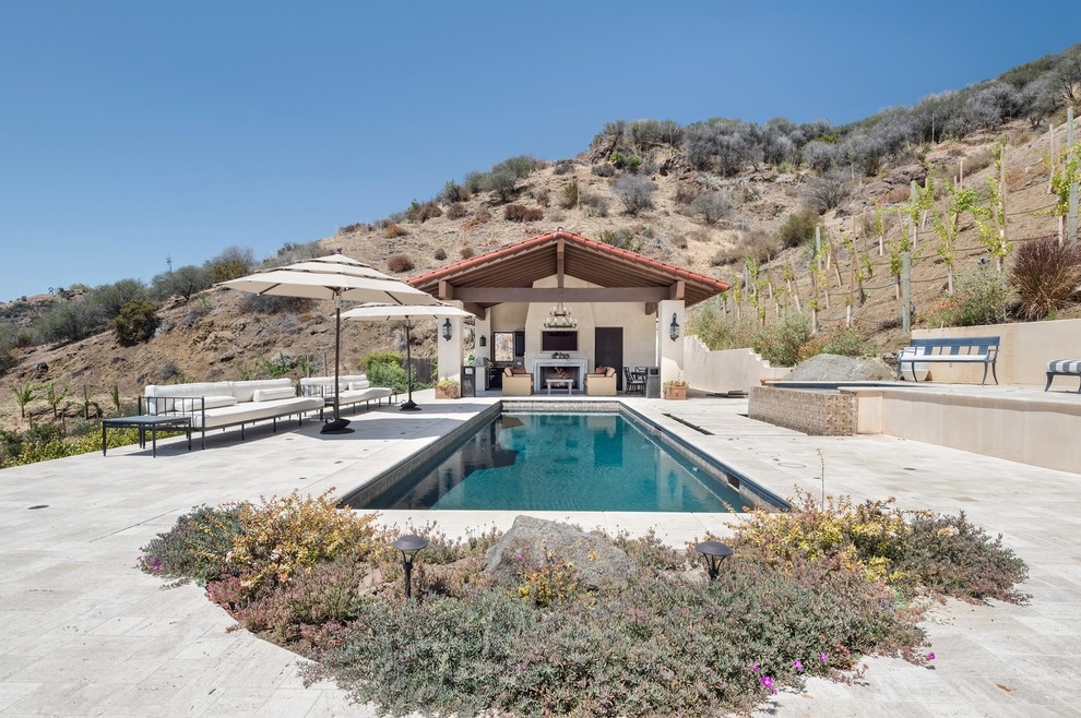 Photo of a large transitional backyard rectangular lap pool in Los Angeles with a hot tub and natural stone pavers.