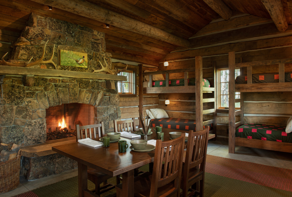 Cette photo montre une petite salle de séjour montagne en bois ouverte avec un mur marron, sol en béton ciré, une cheminée standard, un manteau de cheminée en pierre, un téléviseur dissimulé, un sol gris et un plafond en bois.