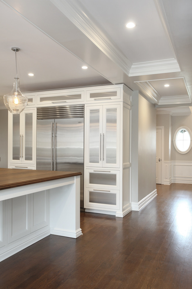 Photo of a large transitional l-shaped eat-in kitchen in New York with a farmhouse sink, recessed-panel cabinets, white cabinets, marble benchtops, stainless steel appliances, medium hardwood floors and with island.