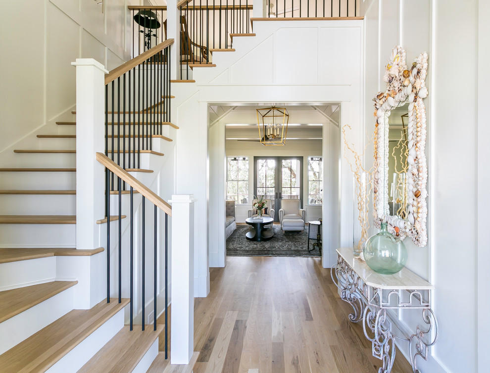 Design ideas for a beach style foyer in Charleston with white walls, light hardwood floors and beige floor.