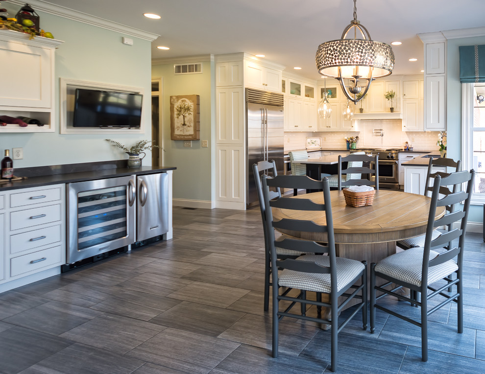 Large mountain style u-shaped medium tone wood floor and brown floor eat-in kitchen photo with an undermount sink, shaker cabinets, white cabinets, solid surface countertops, white backsplash, subway tile backsplash, stainless steel appliances and an island