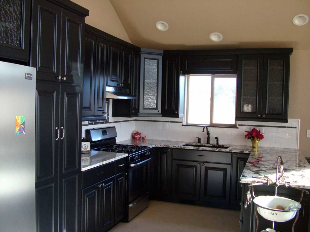 Mid-sized transitional u-shaped light wood floor open concept kitchen photo in Denver with an undermount sink, beaded inset cabinets, black cabinets, marble countertops, white backsplash, subway tile backsplash, stainless steel appliances and a peninsula