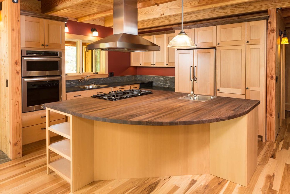 Open concept kitchen - craftsman light wood floor open concept kitchen idea with stainless steel appliances, an island, a drop-in sink, light wood cabinets, multicolored backsplash and stone tile backsplash