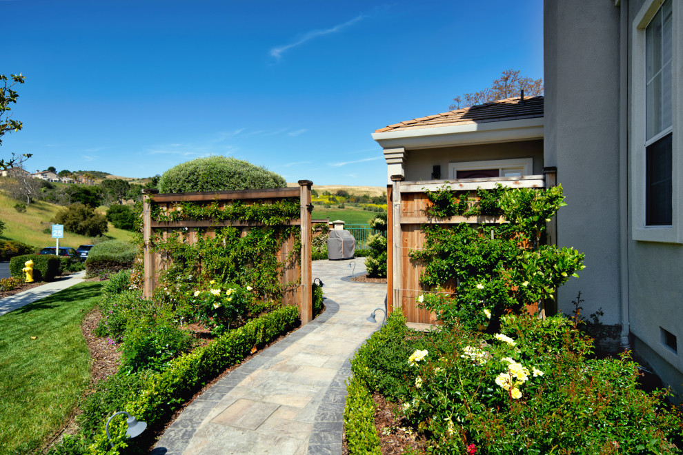 Diseño de jardín mediterráneo grande en patio lateral con camino de entrada, exposición total al sol, adoquines de hormigón y con madera