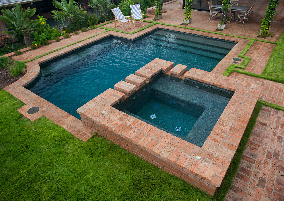 Small traditional backyard custom-shaped lap pool in Austin with brick pavers and a hot tub.