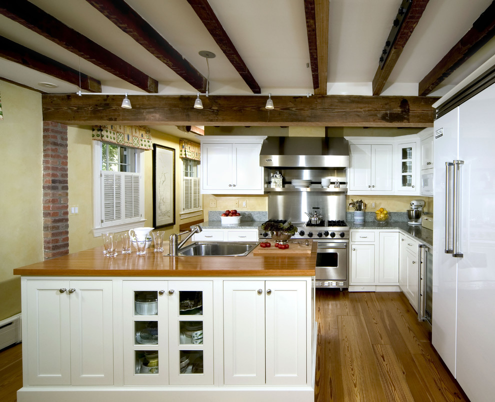 Inspiration for a traditional kitchen in DC Metro with recessed-panel cabinets, white appliances, wood benchtops, a drop-in sink and white cabinets.