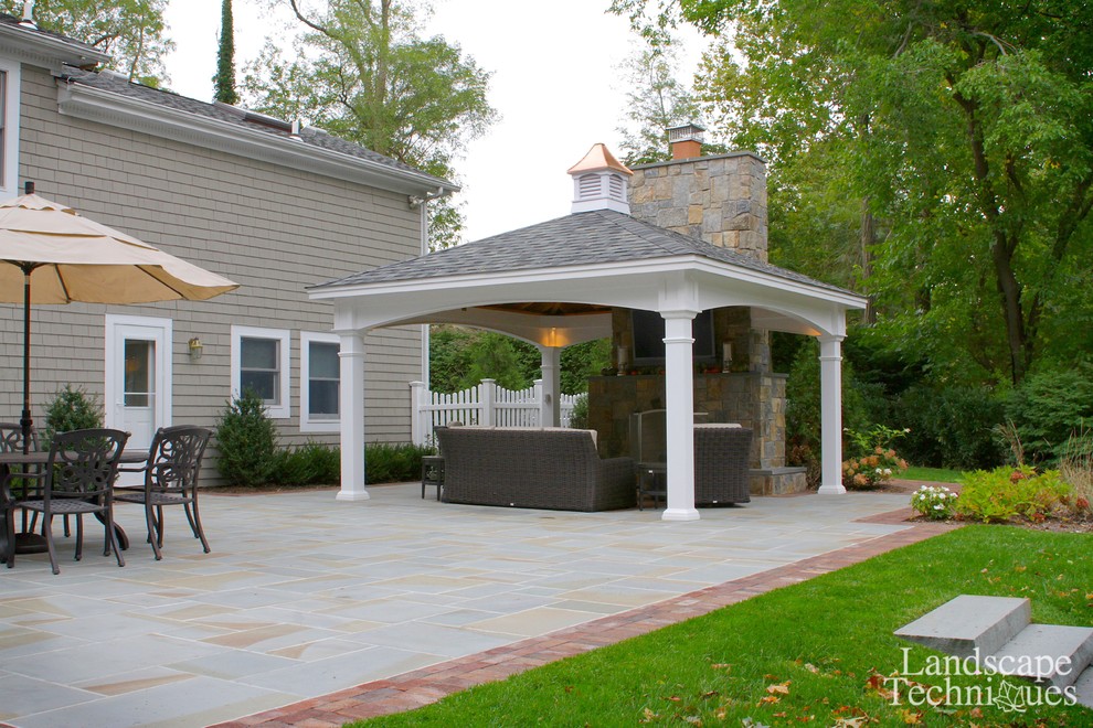 Large country backyard patio in New York with a fire feature, natural stone pavers and a gazebo/cabana.